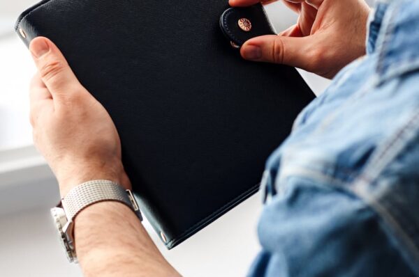 close up of hands holding a black leather portfolio