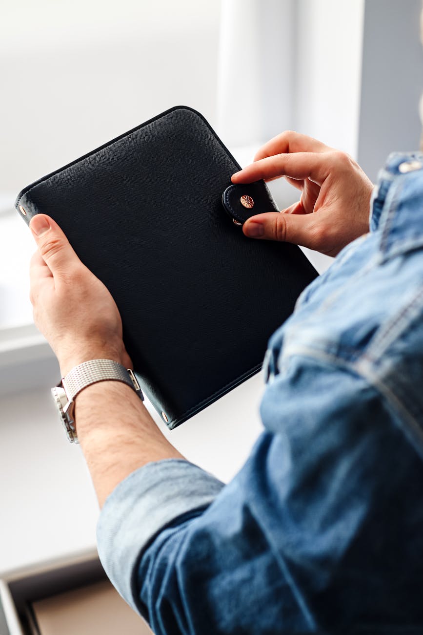 close up of hands holding a black leather portfolio